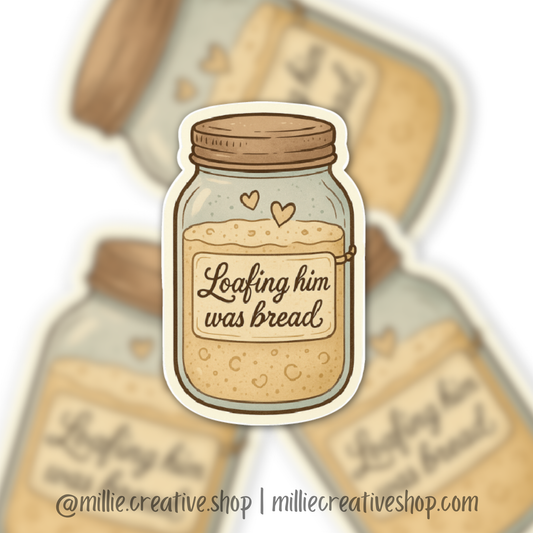 Sticker of a jar of sourdough bread starter labeled 'Loafing him was bread' with a blurred background