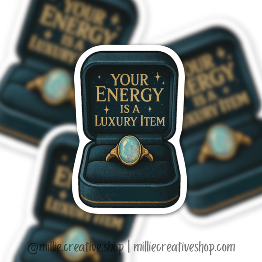 Sticker with a ring in a box and text 'Your Energy is a Luxury Item' on a blurred background.